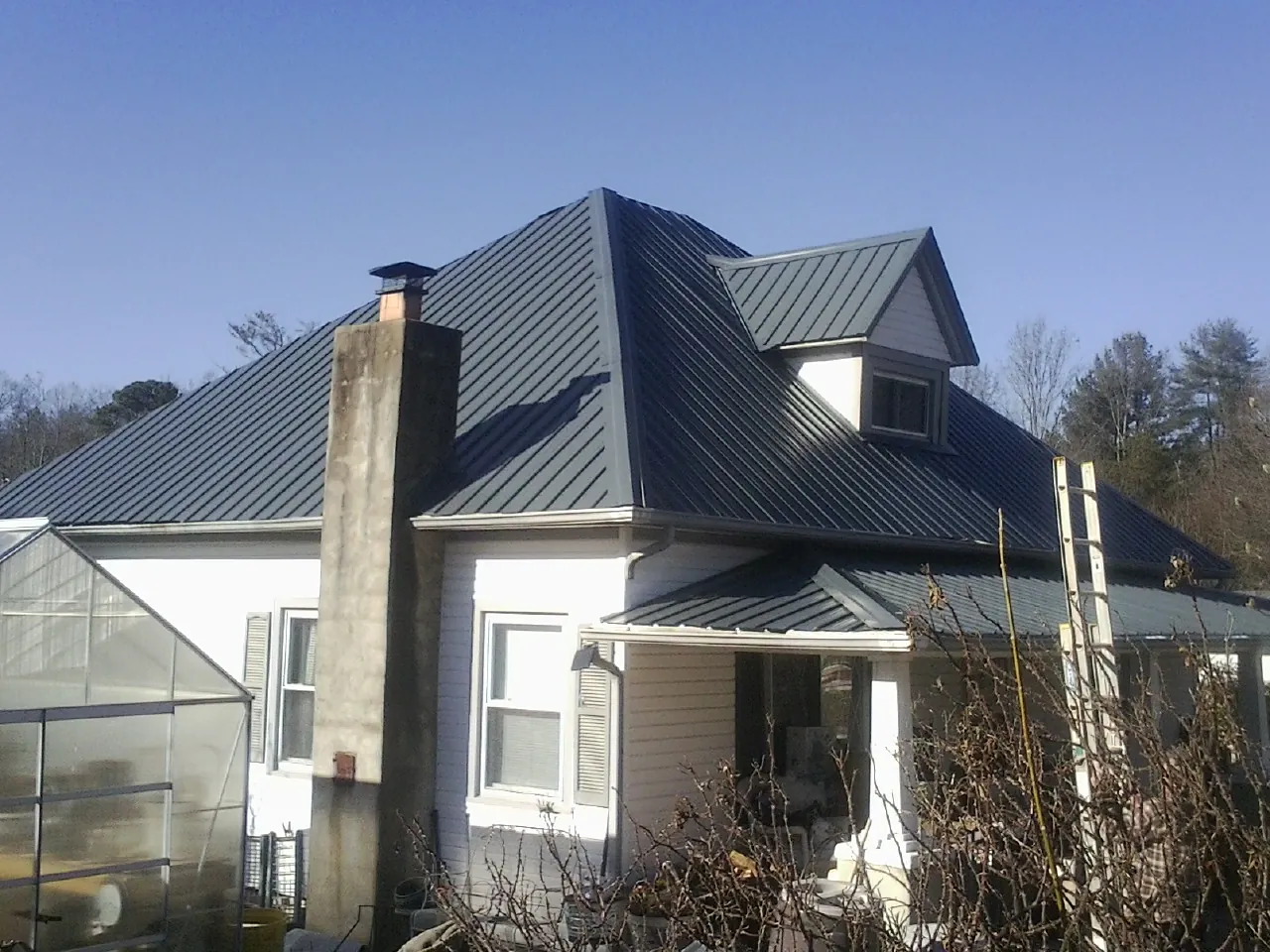Dark blue standing seam metal roof on a white farmhouse with dormer — Slate & Tile Roof Repair by Roofing Brothers in Powhattan