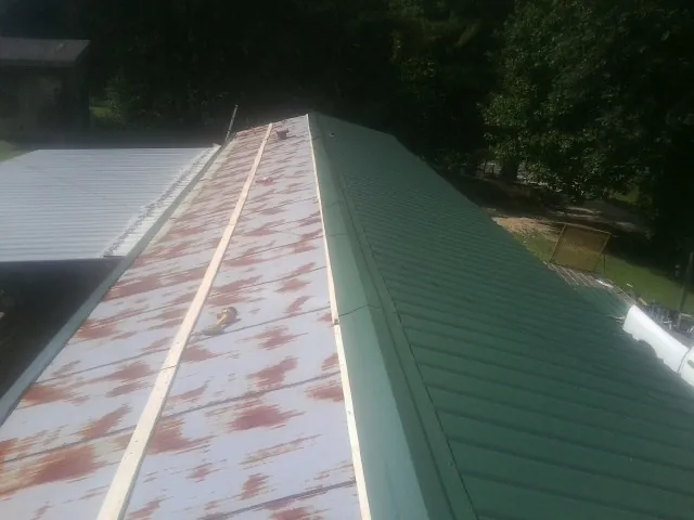 Old rusted panels beside newly installed green metal roofing — Wind Damage Roof Repair by Roofing Brothers in Powhattan