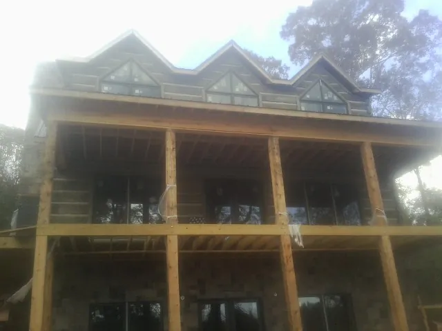 Dormers and porch framing on a large log home under construction — Roof Coating work by our crew in Powhattan