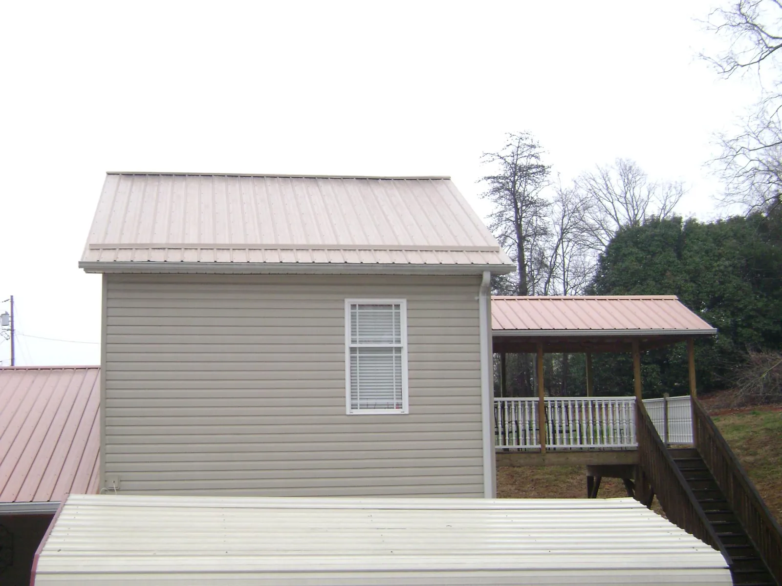 Tan metal roofs on a two story addition and attached porch, from a Roof Replacement job in Powhattan