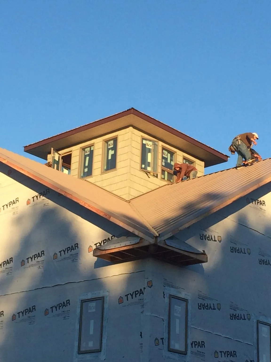 Roofers working around a rooftop cupola on a new metal roof at sunset — Roof Waterproofing in Powhattan by Roofing Brothers